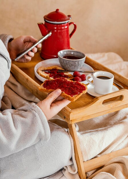 Mano de primer plano sosteniendo una rebanada de pan con mermelada