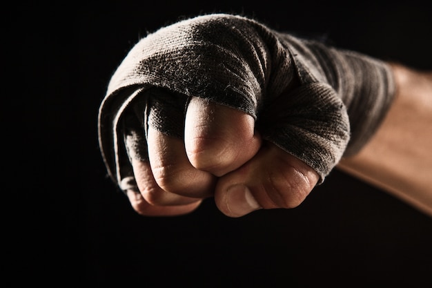 Mano de primer plano con vendaje de kickboxing de entrenamiento de hombre musculoso en negro