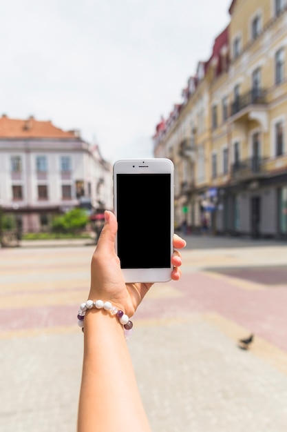 Foto gratuita mano con pulsera con smartphone en la calle