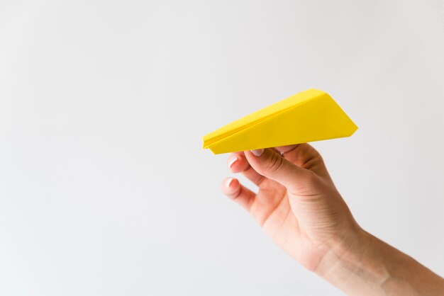 Mano que sostiene el avión de papel amarillo