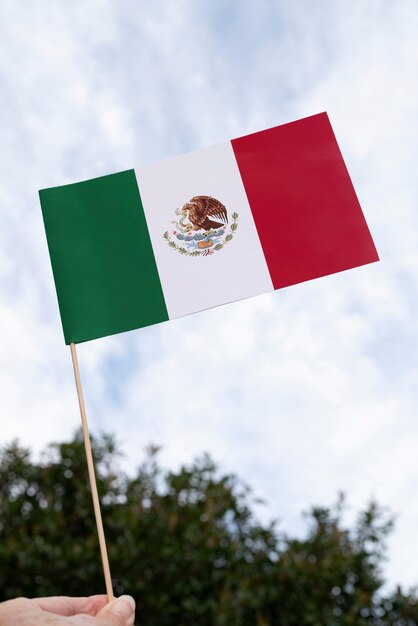 Mano que sostiene la bandera mexicana al aire libre