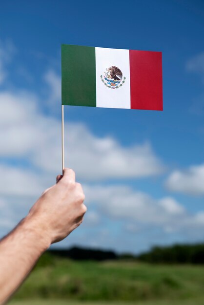 Mano que sostiene la bandera mexicana al aire libre