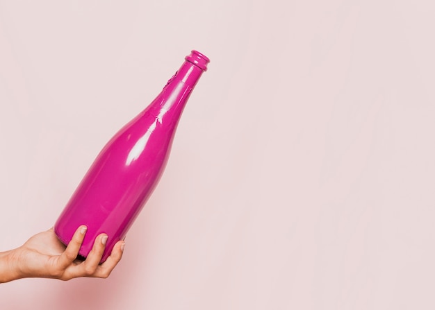 Mano que sostiene la botella de champán rosa