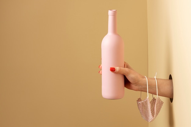 Mano que sostiene la botella rosa de cerca