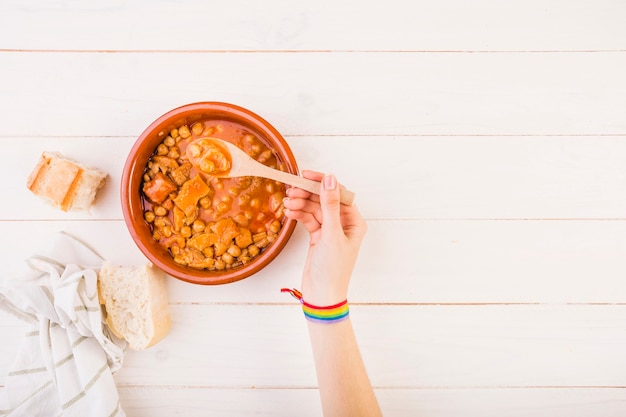 Mano que sostiene la cuchara con comida en la mesa