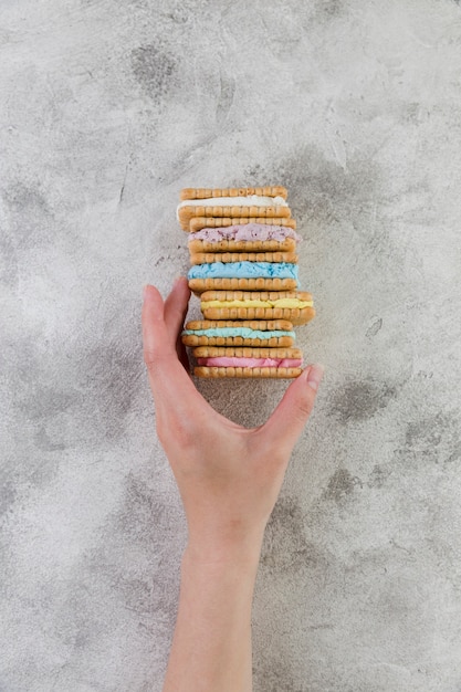 Foto gratuita mano que sostiene las galletas con helado sobre fondo gris