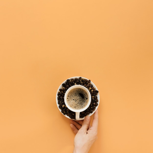 Foto gratuita mano que sostiene el plato con una taza de café