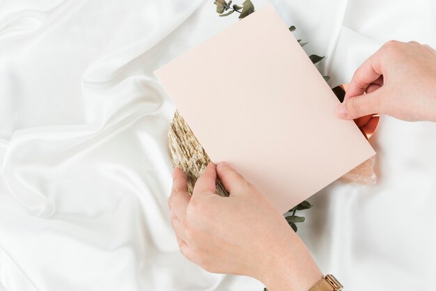 Mano que sostiene la tarjeta de invitación en blanco rosa