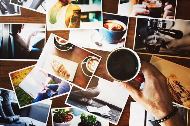 La mano que sostiene la taza de café con puede fotografiar sobre la mesa
