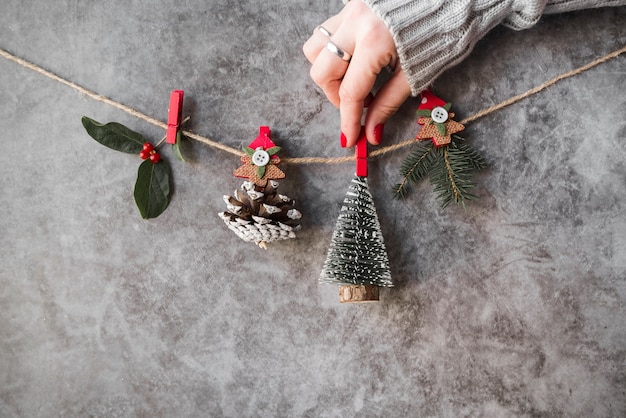 Foto gratuita mano que sujeta adornos navideños en hilo