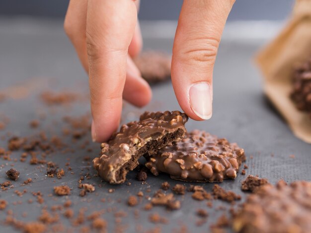 Mano que toma la galleta de chocolate pellizcada de la mesa