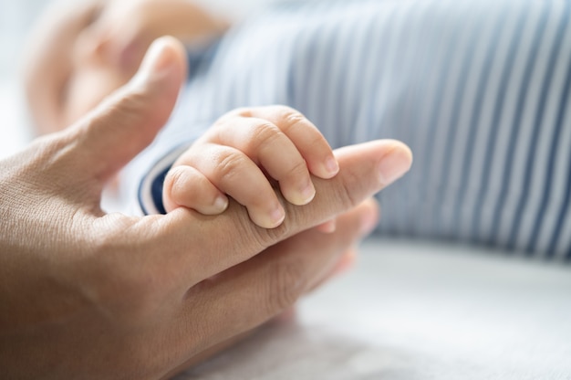 La mano del recién nacido que sostiene los dedos de la madre