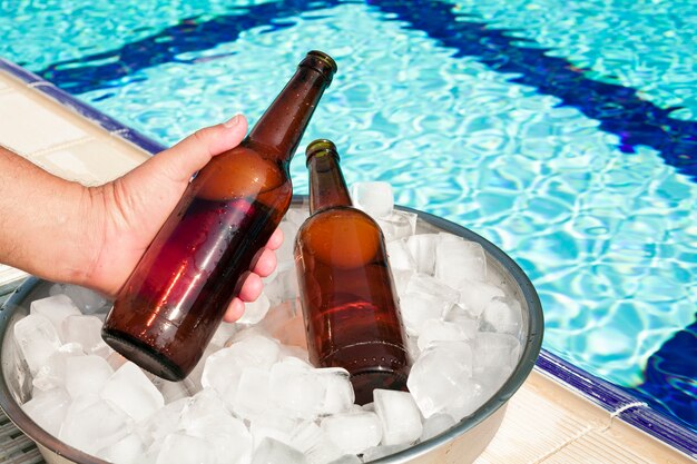 Mano sacando una botella de cerveza de la bandeja con hielo