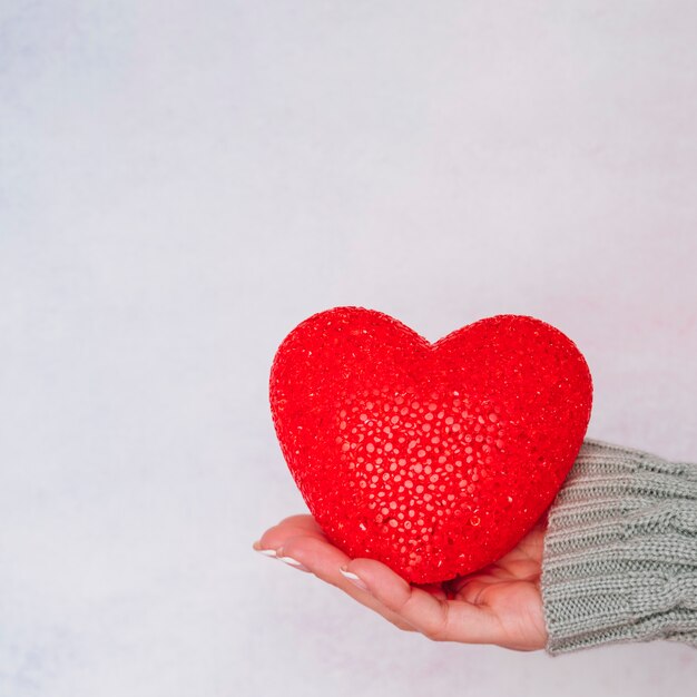 Mano de señora con corazón decorativo.