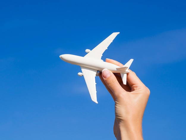 Foto gratuita mano sosteniendo un avión en el cielo