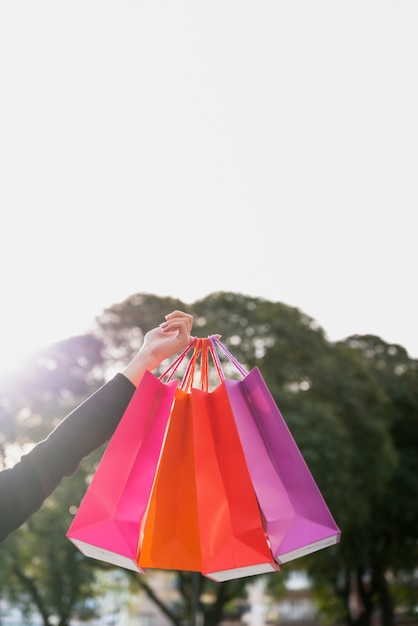 Foto gratuita mano sosteniendo bolsas con árbol detrás