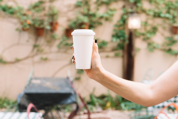 Mano sosteniendo café para llevar