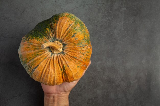 Mano sosteniendo calabaza en piso oscuro