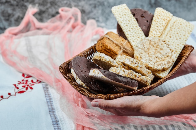 Mano sosteniendo una canasta de galletas mixtas.