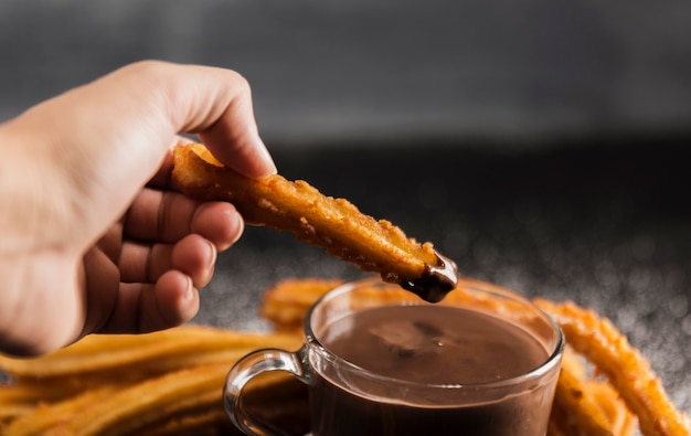 Foto gratuita mano sosteniendo un churros fritos con chocolate