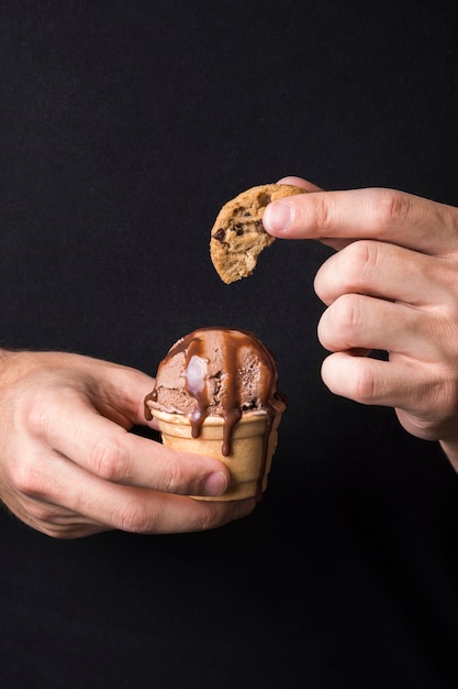 Foto gratuita mano sosteniendo delicioso helado con galleta