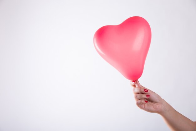 Mano sosteniendo un globo en forma de corazón