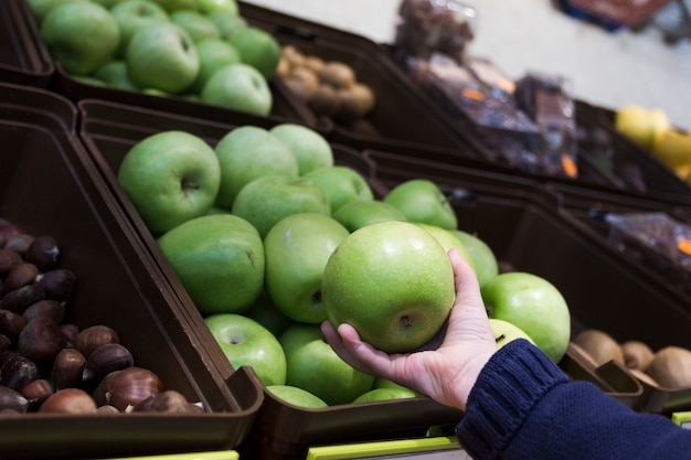 Mano sosteniendo la manzana en la tienda