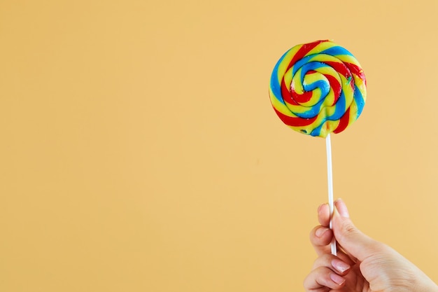 Mano sosteniendo paletas de colores sobre fondo naranja.