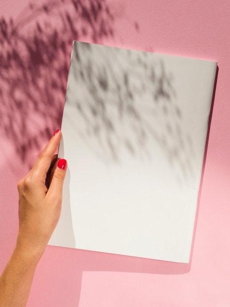 Foto gratuita mano sosteniendo papel en blanco con sombras