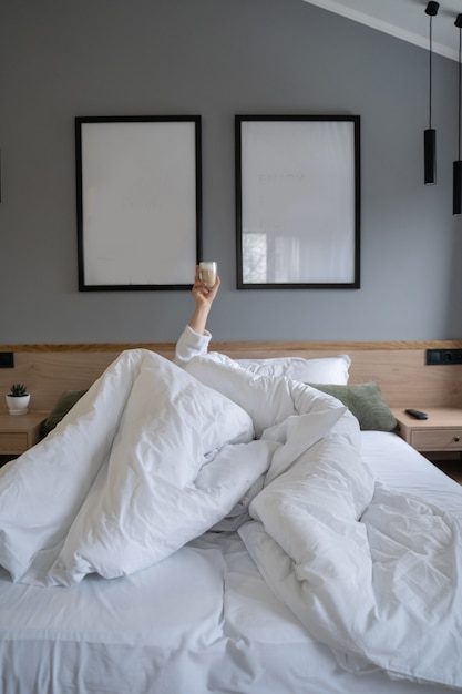 Foto gratuita mano sosteniendo una taza de café en su casa en la cama