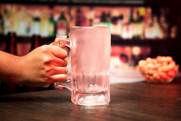 Mano sosteniendo vaso de cerveza vacío