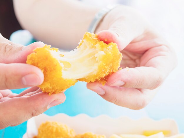 La mano sostiene una bola de queso elástica lista para ser consumida sobre un fondo de mesa azul