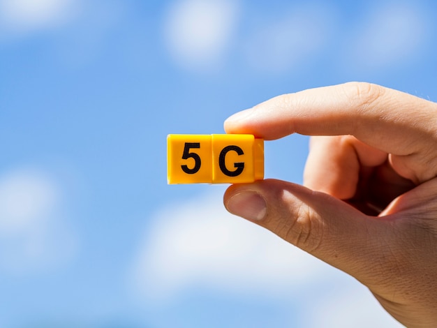 Mano sujetando 5g snap cubos contra el cielo con nubes