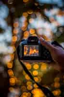 Foto gratuita mano sujetando una cámara digital sobre un fondo de luces bokeh