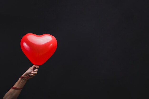 Mano sujetando un globo con forma de corazón