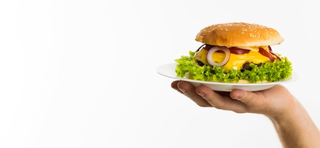 Mano sujetando la hamburguesa en el plato con espacio de copia