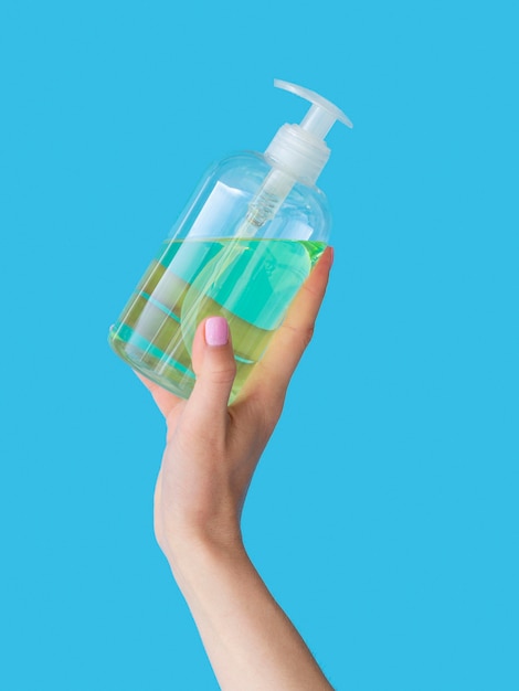 Foto gratuita mano sujetando jabón líquido en botella de plástico