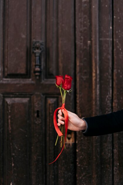 Mano sujetando ramo de rosas rojas