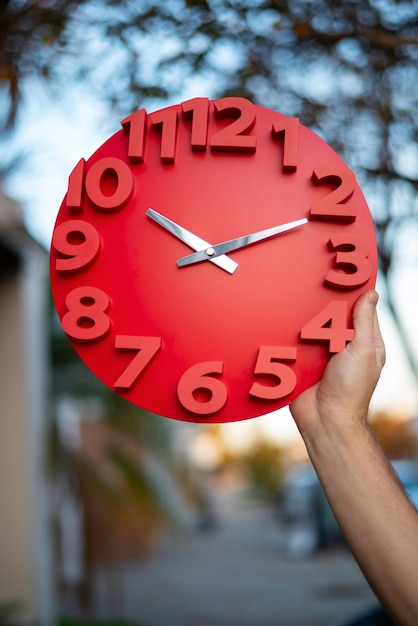 Foto gratuita mano sujetando reloj de pared bodegón