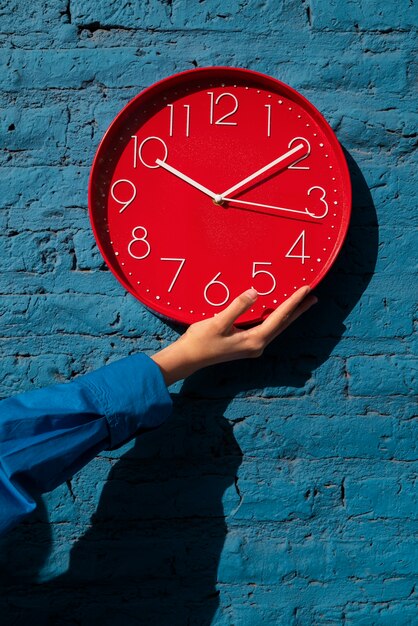 Mano sujetando reloj de pared bodegón