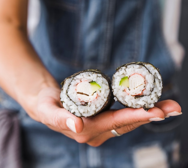 Foto gratuita mano sujetando rollos de sushi