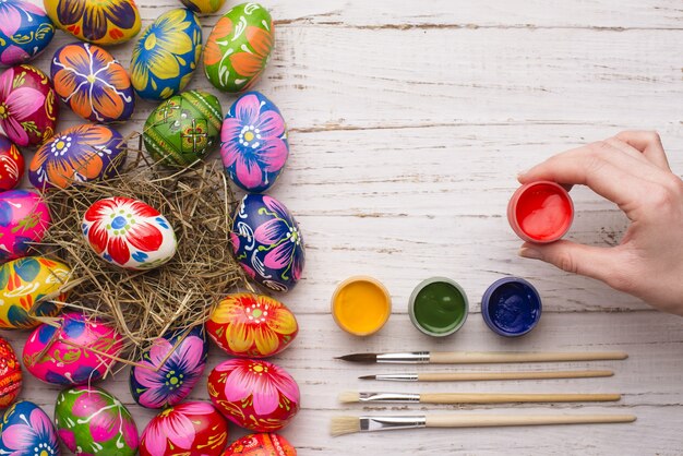 Mano sujetando un tarro de pintura junto a huevos de pascua