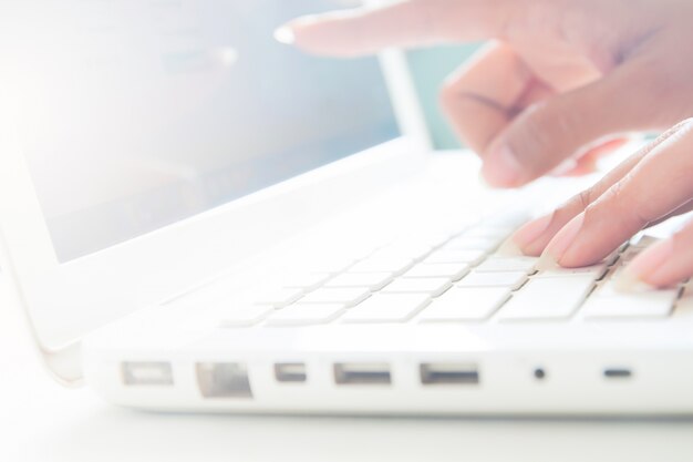 Mano en el teclado y el punto a la pantalla de la computadora portátil, Concepto de negocio con espacio de la copia