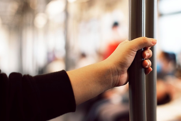 Mano tocando un pasamanos de tren contaminado con coronavirus