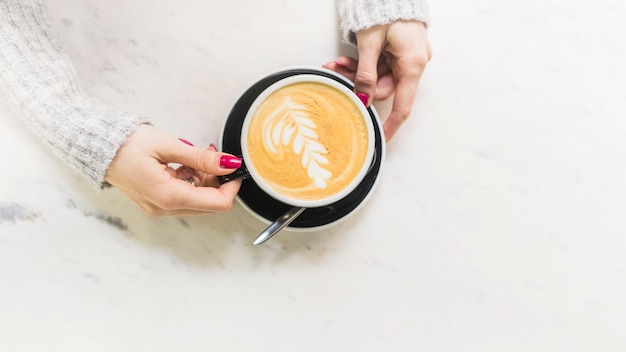 Mano tomando la taza con café