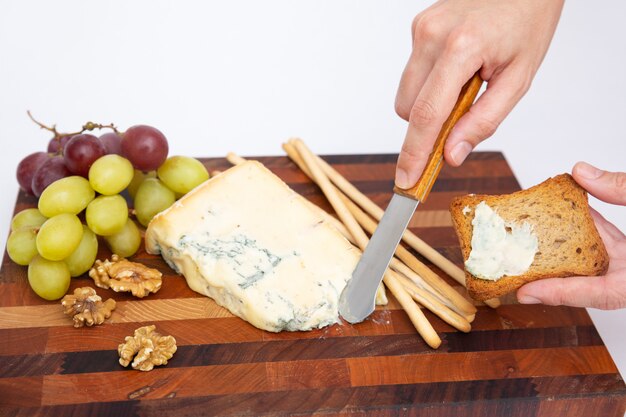 Mano para untar queso azul sobre pan sobre tabla para cortar