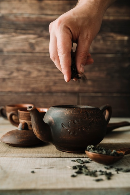 Foto gratuita mano vertiendo hierbas de té en una vista frontal de la tetera