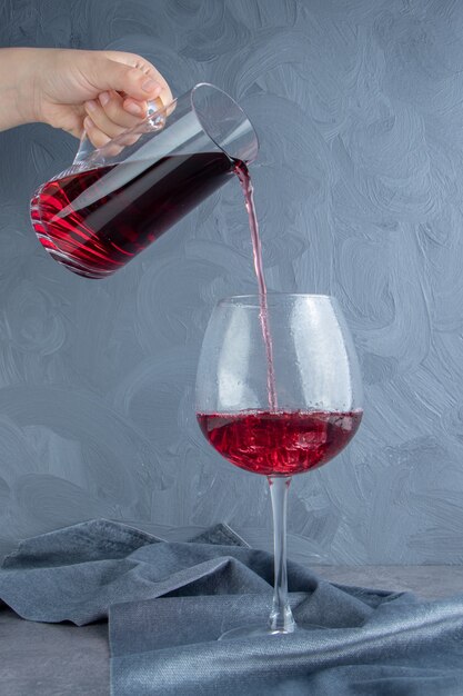 Foto gratuita mano vertiendo jugo de granada en un vaso con cubitos de hielo