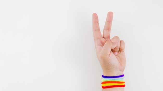 Mano de victoria con pulsera de la bandera del orgullo