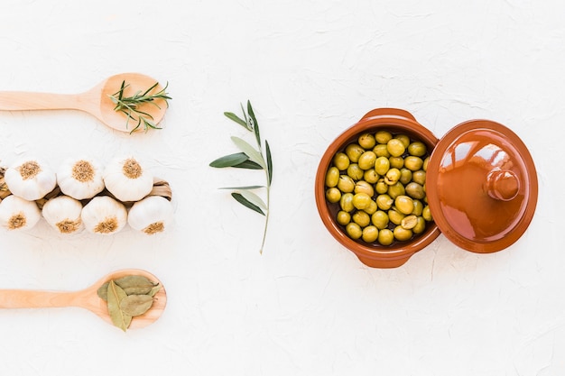 Manojo de bulbos de ajo con hierbas y aceitunas verdes frescas